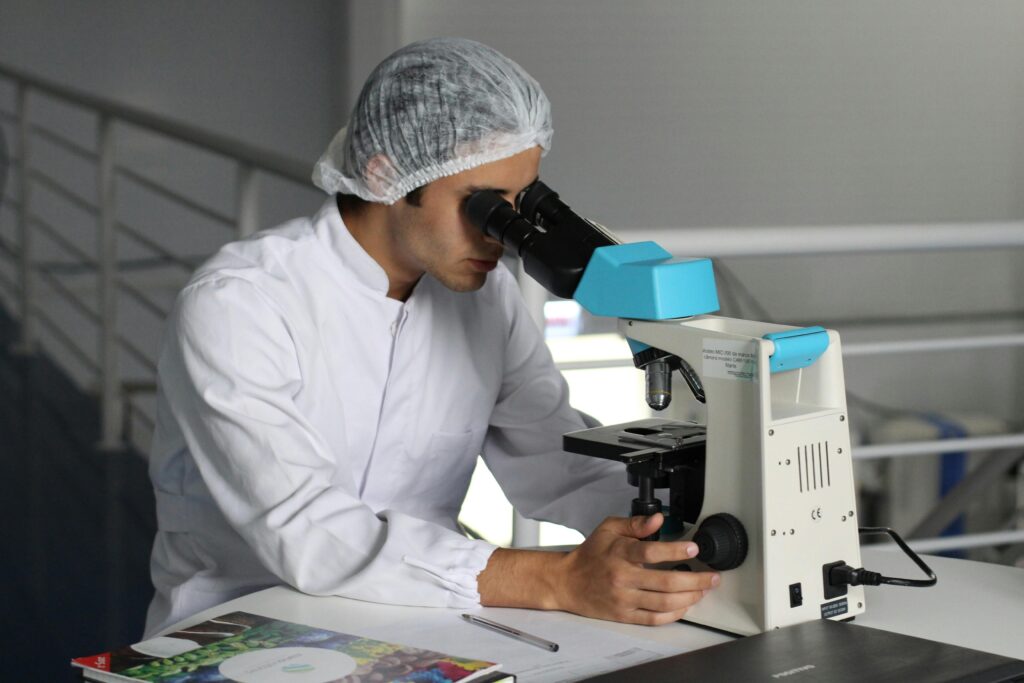pexels-photo-356040-356040 Scientist in a lab coat using a microscope to conduct research, focusing on healthcare improvements.